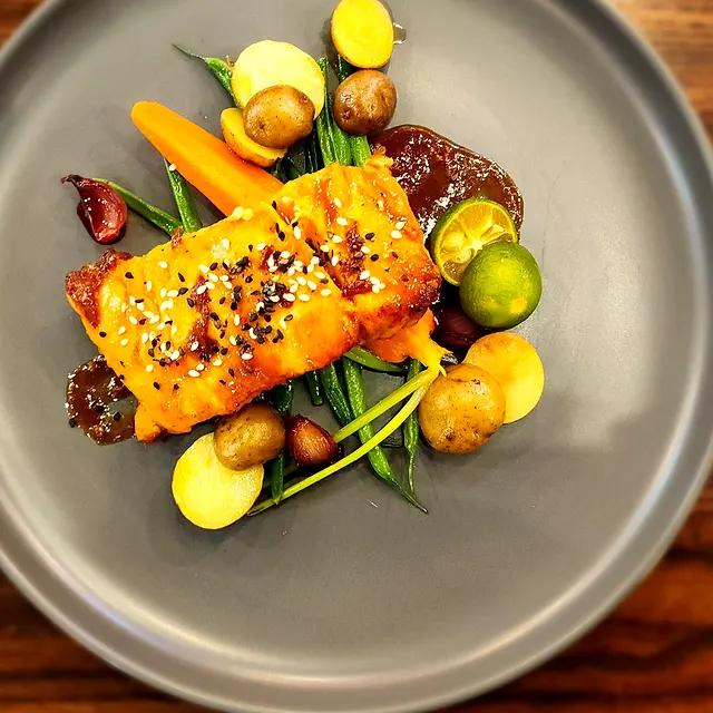 Glazed salmon with sesame, green beans, potatoes and calamansi on a grey plate