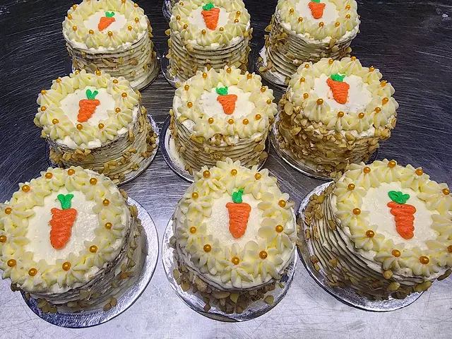 Rows of mini carrot cakes with piped frosting and carrot decorations