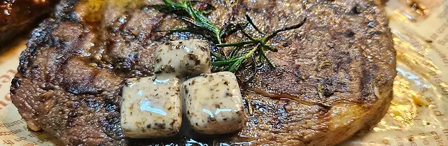 Grilled steak topped with herb butter cubes and rosemary