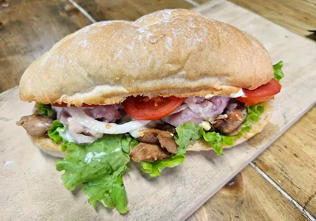Gourmet sub sandwich with roast meat, tomato and lettuce on a crusty roll